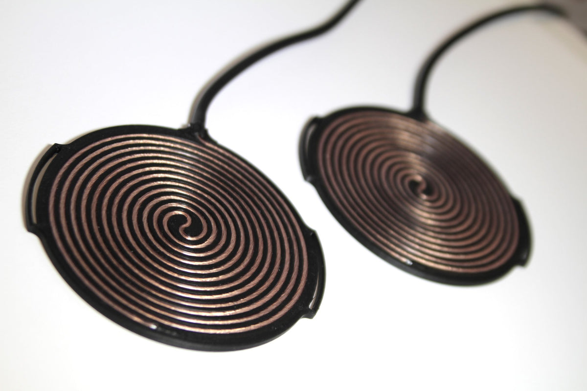 Pair of Tvíburi pads photographed at an angle showing depth and finish of the copper winding